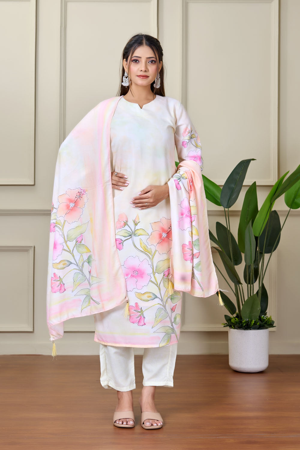 Woman wearing a floral outfit standing indoors with a plant in the background