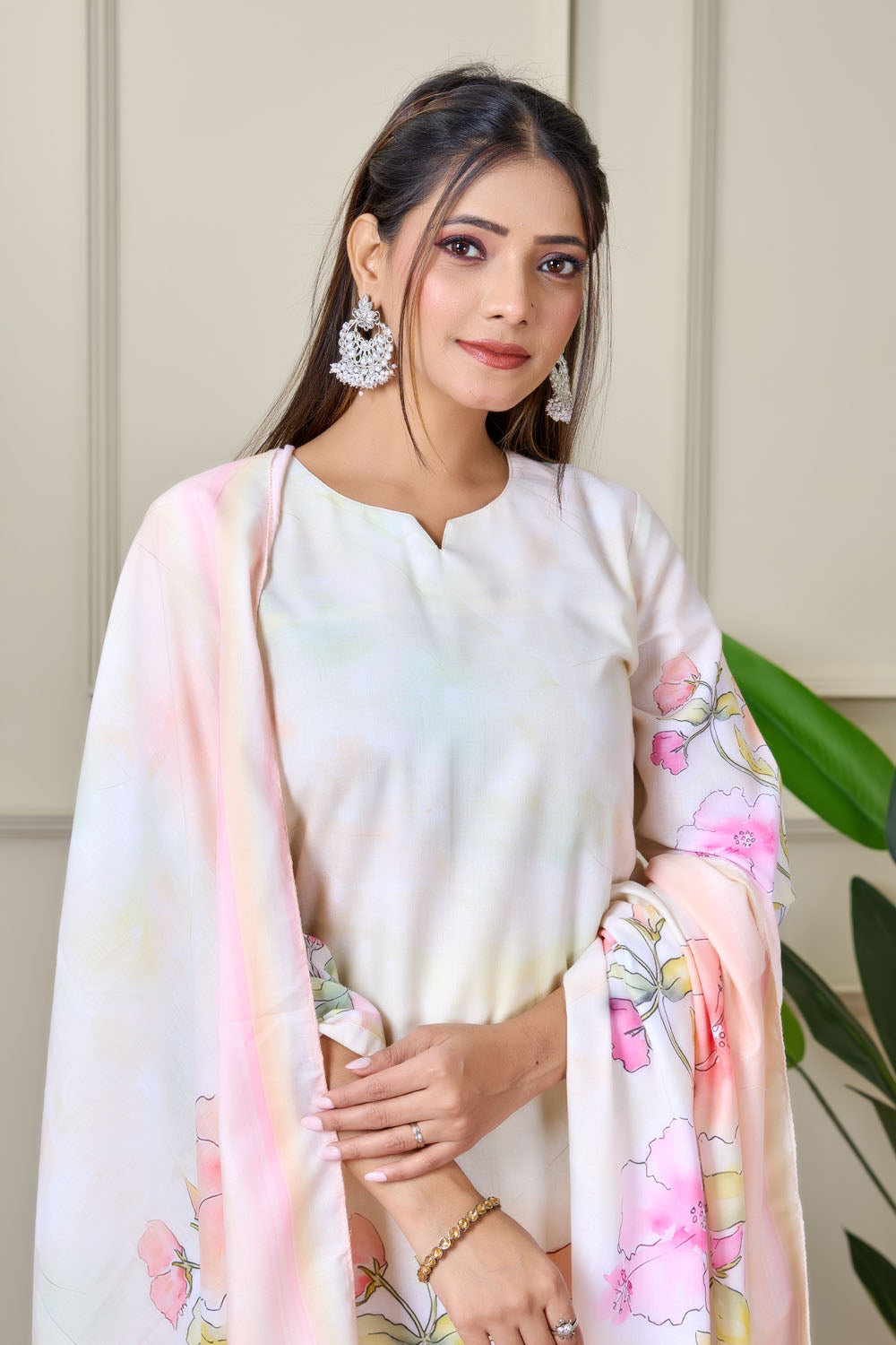 Woman wearing a floral outfit standing indoors with a plant in the background